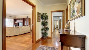 A hallway with wooden flooring, a blue patterned rug, a wooden console table, and a statue. - Monumental Ocean View by Atlantic Holiday (Funchal)