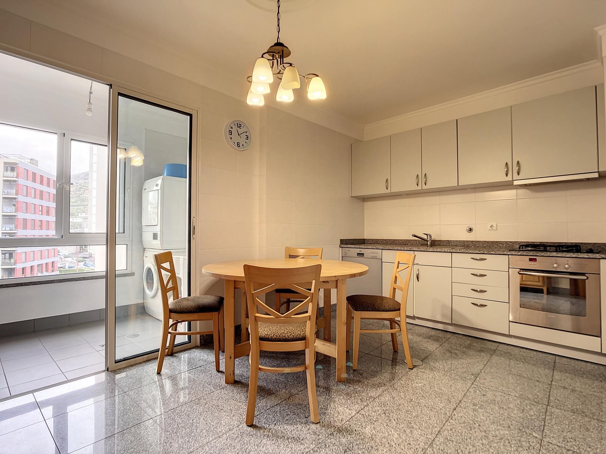 A modern kitchen with a dining table, chairs, and a built-in oven.