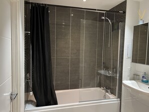 Ein modernes Badezimmer mit einer Badewanne, einer Dusche und einem Waschbecken mit Spiegel.
