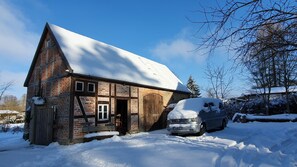 A traditional half-timbered house with a snow-covered roof and a parked car in front. - Hunter's apartment in the Großmenow forester's lodge (Fürstenberg/Havel)