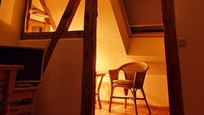 A room with a sloped ceiling, wooden beams, a chair, and a table.
