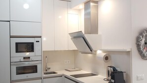 Une cuisine moderne dotée d’appareils électroménagers intégrés, d’une hotte en acier inoxydable et d’une machine à café posée sur le plan de travail.