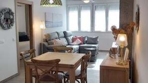 Un salon moderne avec un canapé, une table à manger et des chaises. On y trouve également un ventilateur de plafond et un luminaire suspendu.