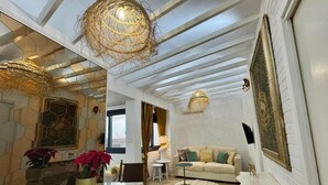 Un interior moderno con una zona de comedor, un conjunto de sofás y una araña.