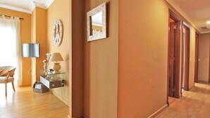 A hotel hallway with wooden flooring, a clock on the wall, a television, and a mirror. - Del Parque Flats Cervantes: Cozy Apartment for 4 in Historic Málaga Center (Málaga)