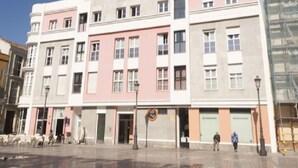 A multi-story building with a ground-floor entrance, a pedestrian area with chairs, and a street lamp. - Del Parque Flats Cervantes: Cozy Apartment for 4 in Historic Málaga Center (Málaga)