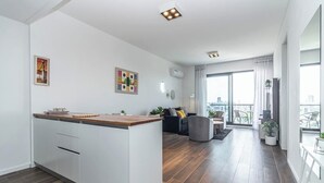 A modern apartment with a kitchen, living area, and balcony with city views.