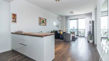 Un apartamento moderno con cocina, sala de estar y balcón con vistas a la ciudad.