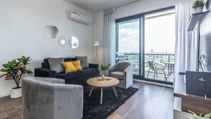 A modern living room with a sofa, armchairs, a coffee table, and a large window with a city view.