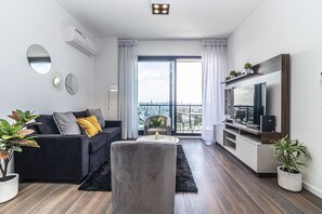 Relax in this stylish living room with a sofa, coffee table, and armchair, offering a view of the city.