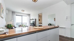 A modern kitchen with a wooden countertop, white cabinets, and a view to the outside.