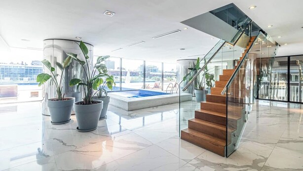 A modern interior with a glass staircase, a pool, and potted plants.