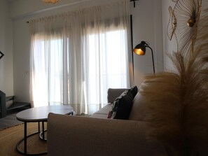 Uma sala de estar com um sofá, uma mesa redonda e um abajur.