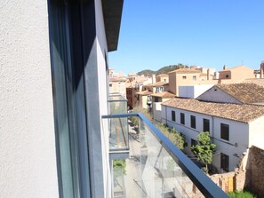 A view from a balcony overlooking a residential area with traditional buildings and a clear sky.