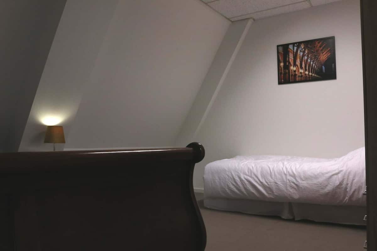 Une chambre à coucher avec un lit, une lampe et un tableau accroché au mur.