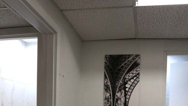 A hallway with white walls, a door with a small window, and a tiled floor.