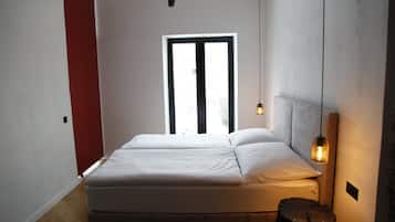 Une chambre à coucher avec un lit, une fenêtre et une table de chevet avec une lampe.