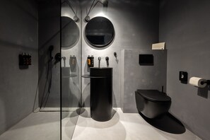 Enjoy a sleek bathroom with a large mirror, black sink, and toilet, plus ample storage on two wall shelves.