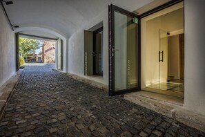 Stroll through the corridor with a clear view of the surrounding architecture and lush greenery.