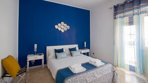 Una habitación de hotel con una cama grande, una mesita de noche, una silla y un adorno en la pared.