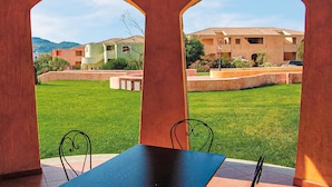 A courtyard with a table and chairs, surrounded by arches, and a building with a tiled roof in the background. - Awesome apartment in Marinella (SS) with house sea view (Marinella (SS))