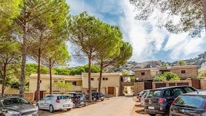 A parking area with several cars, a row of buildings with stone walls, and trees in the foreground. - Awesome apartment in Marinella (SS) with house sea view (Marinella (SS))