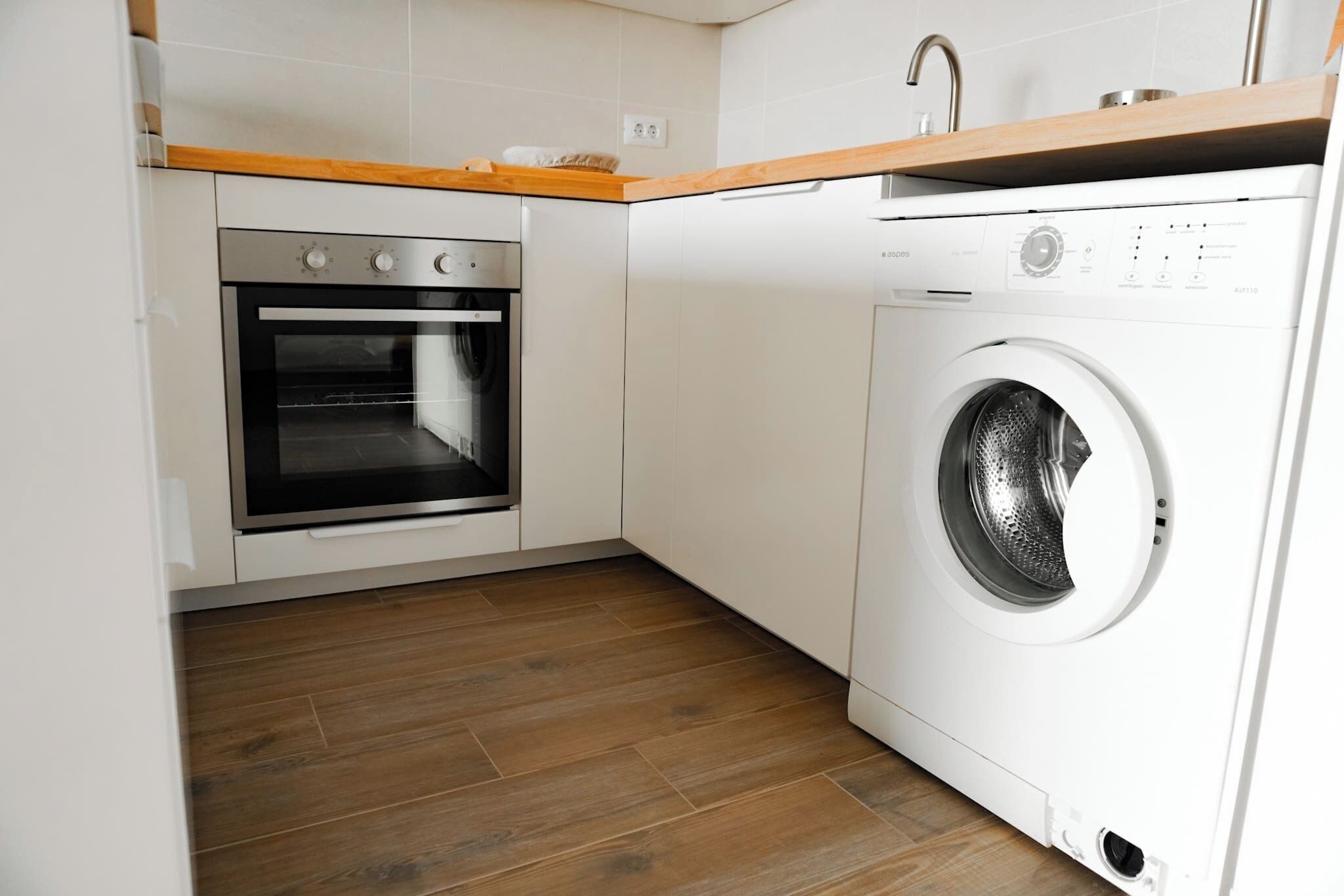 Een compacte keuken met een inbouwoven en een voorlader wasmachine.