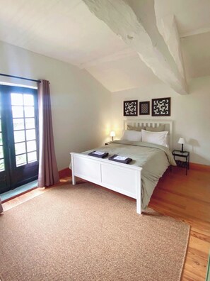 A bedroom with a bed, a nightstand, a window with curtains, and three wall-mounted decorative items. - Le Noyer - at Manoir Bourgale, central Dordogne, 50 acre private park. (Villefranche-du-Périgord)