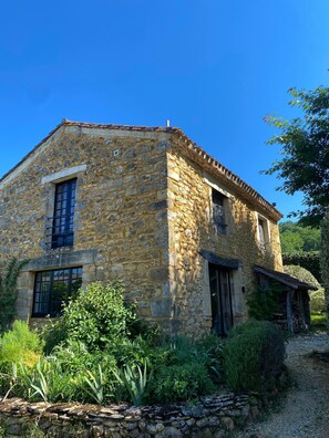 A stone building with a sloped roof, a window, and a door. - Le Noyer - at Manoir Bourgale, central Dordogne, 50 acre private park. (Villefranche-du-Périgord)