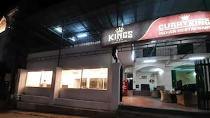 Een gebouw met een bord waarop 'Kings Luxury Hotel' en 'Curry King Indian Restaurant' staat.