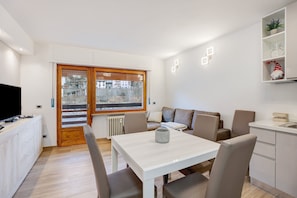 A modern living room with a dining table, sofa, and a TV.