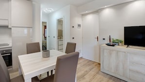 A modern kitchen with a dining area, a TV on a cabinet, and a refrigerator. - Apartment 'Gianpaolo' with Mountain View, Shared Garden and Wi-Fi (Piode)