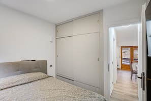 A bedroom with a bed, a wardrobe, and a door leading to another room.