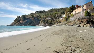 Una spiaggia con impronte, cielo sereno e edifici su una collina.