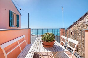 Un balcon avec une table, des chaises et un pot de fleurs.