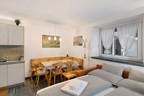 Quarto compacto com cama, mesa de jantar e cozinha compacta.