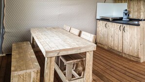 Una mesa de comedor de madera con bancos, una zona de cocina con armarios de madera y una pared acolchada.