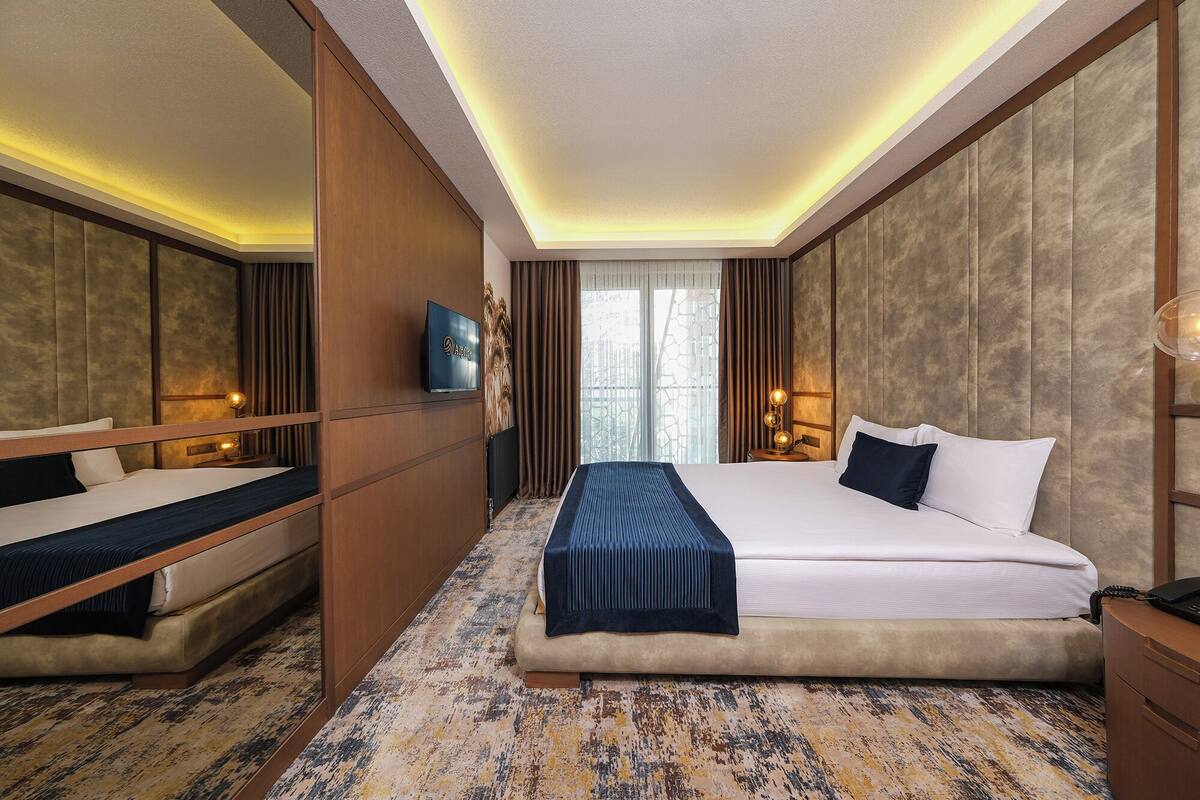 A hotel room with a bed, bedside table, lamp, and a television.