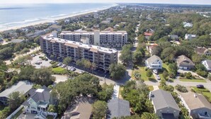 A multi-story hotel with a central courtyard, surrounded by residential buildings and a beach view. - Nice Condo, Partial Ocean Views, Pool-307 Litchfield Retreat (Pawleys Island)