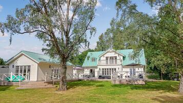 A two-story house with a green roof, white siding, and a front porch.