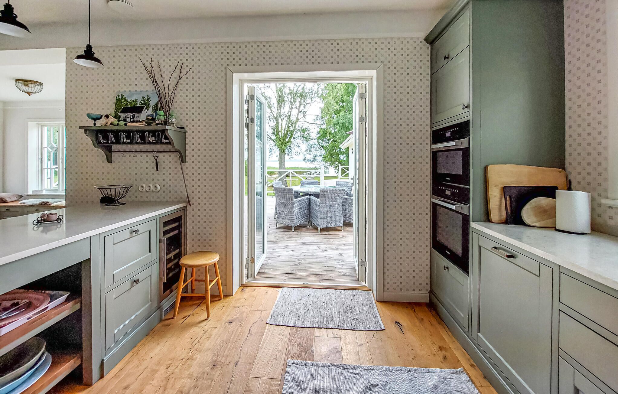 Une cuisine compacte avec un plancher en bois, un coin repas avec des sièges extérieurs et une vue à travers une porte vitrée.