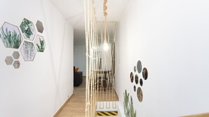 Un pasillo con piso de madera, una escalera con barandilla de cuerda y decoración mural hexagonal.