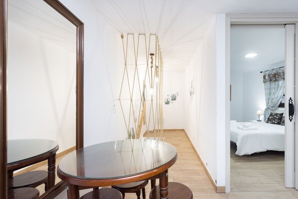A hotel room with a bed, a bathroom, and a dining area with a glass table and chairs.