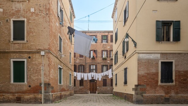 A narrow alley with buildings on either side, featuring laundry hanging between them.