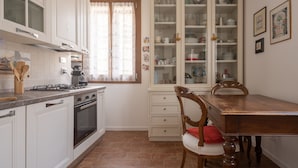 A kitchen with white cabinets, a stove, and a dining table with chairs.