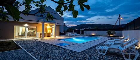 A modern house with a swimming pool, outdoor seating, and a patio area.