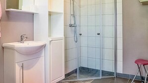 A bathroom with a white sink, a glass shower enclosure, and a red stool. - Lovely home in Visby with WiFi (Visby)