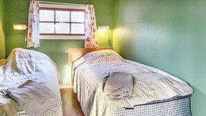 A room with two single beds, a window with floral curtains, and a wall-mounted lamp. - Lovely home in Visby with WiFi (Visby)