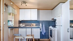 A compact kitchen with white cabinets, a blue tiled backsplash, a white refrigerator, and two stools. - Lovely home in Visby with WiFi (Visby)