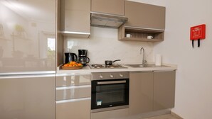 Cozinha moderna com eletrodomésticos de aço inoxidável, forno embutido e máquina de café.